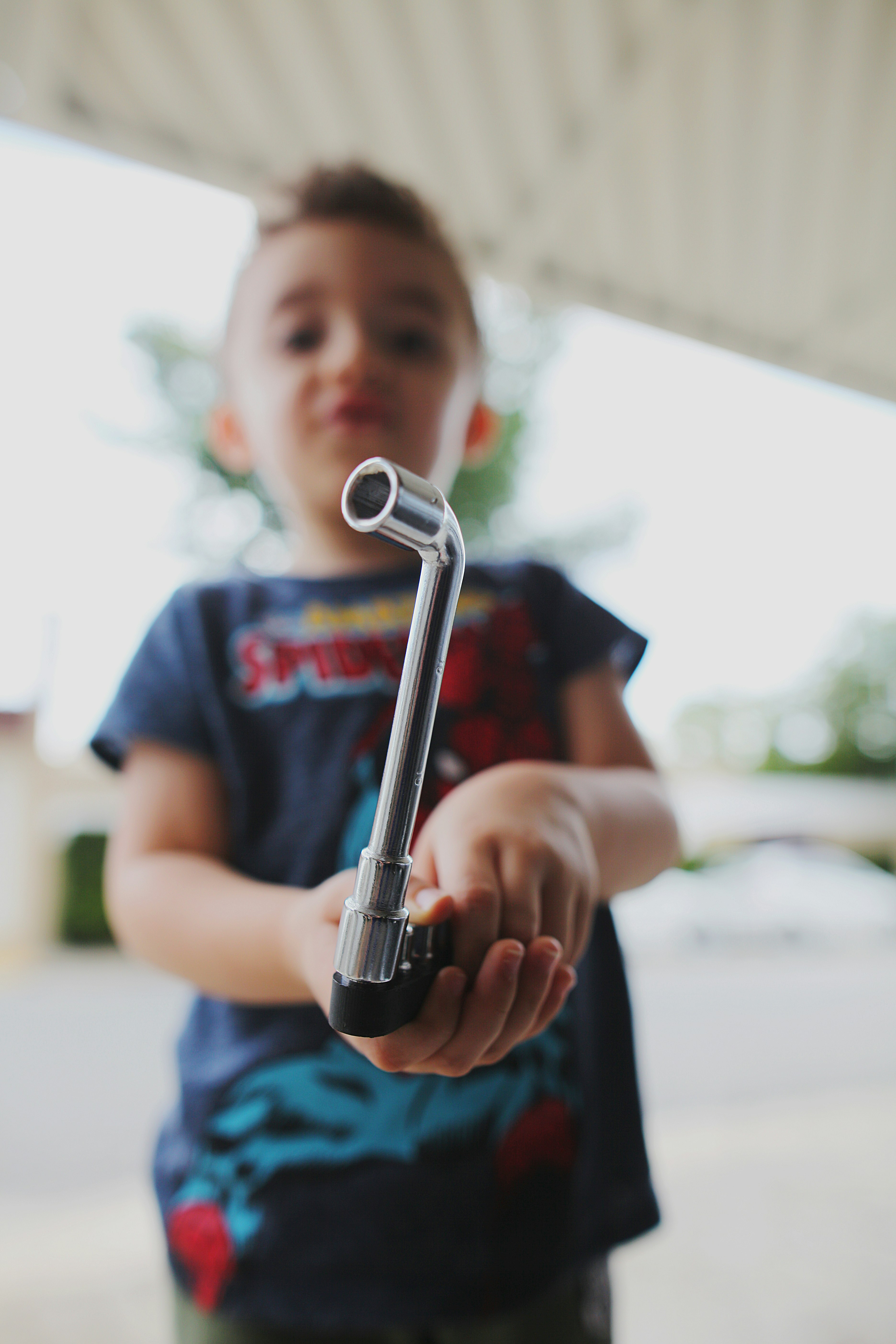 boy in blue crew neck t-shirt holding black and silver hand tool